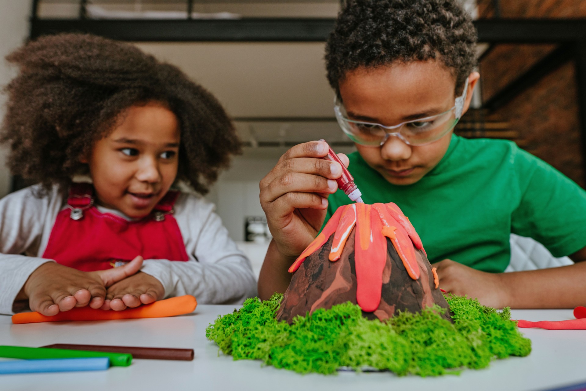 Children making DIY volcano model from kids play clay